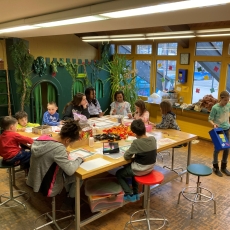 Viele Kinder basteln am Tisch und spielen am Boden