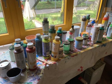 Eine grosse Menge an verschiedenen Farbflaschen und Gläsern stehen auf einer Werkbank