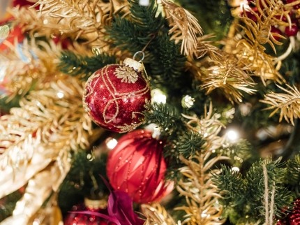Rote Weihnachtskugeln an goldig geschmücktem Tannenbaum