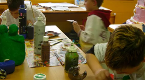 Kinder sitzen an einem Tisch und malen