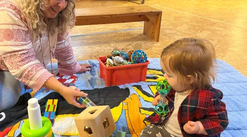 Beraterin der Elternberatung auf Spielzeugdecke mit Kleinkind