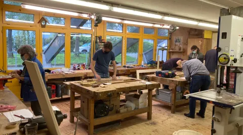 Verschiedene Menschen arbeiten in der Holzwerkstatt