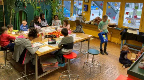 Viele Kinder basteln am Tisch und spielen am Boden
