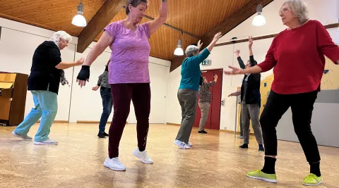 Seniorinnen tanzen frei in einer Gruppe zu Musik
